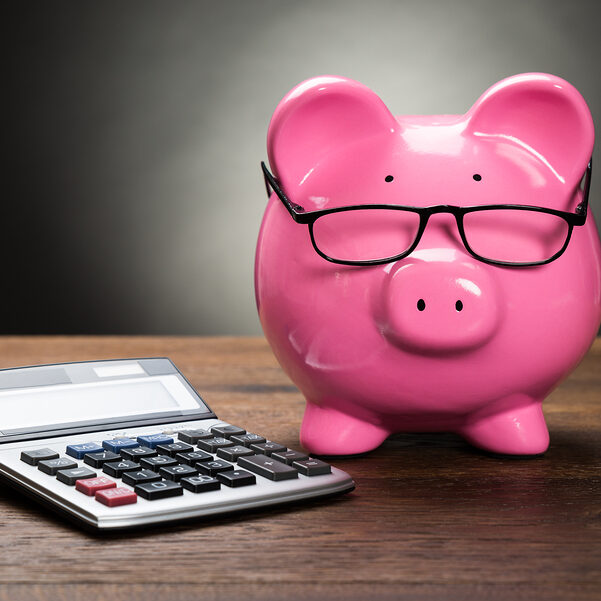 Pink Piggybank With Calculator On Wooden Table